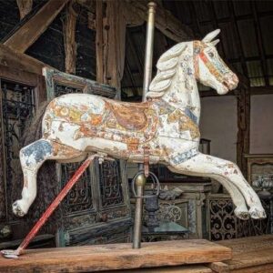 Bemaltes hölzernes Karussellpferd auf einer historischen Jahrmarktskulisse